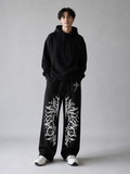 Person wearing a black hoodie and black pants with white patterns on a gray background