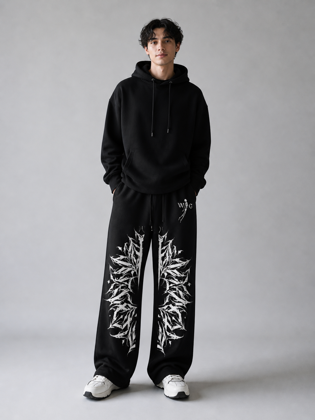 Person wearing a black hoodie and black pants with white patterns on a gray background